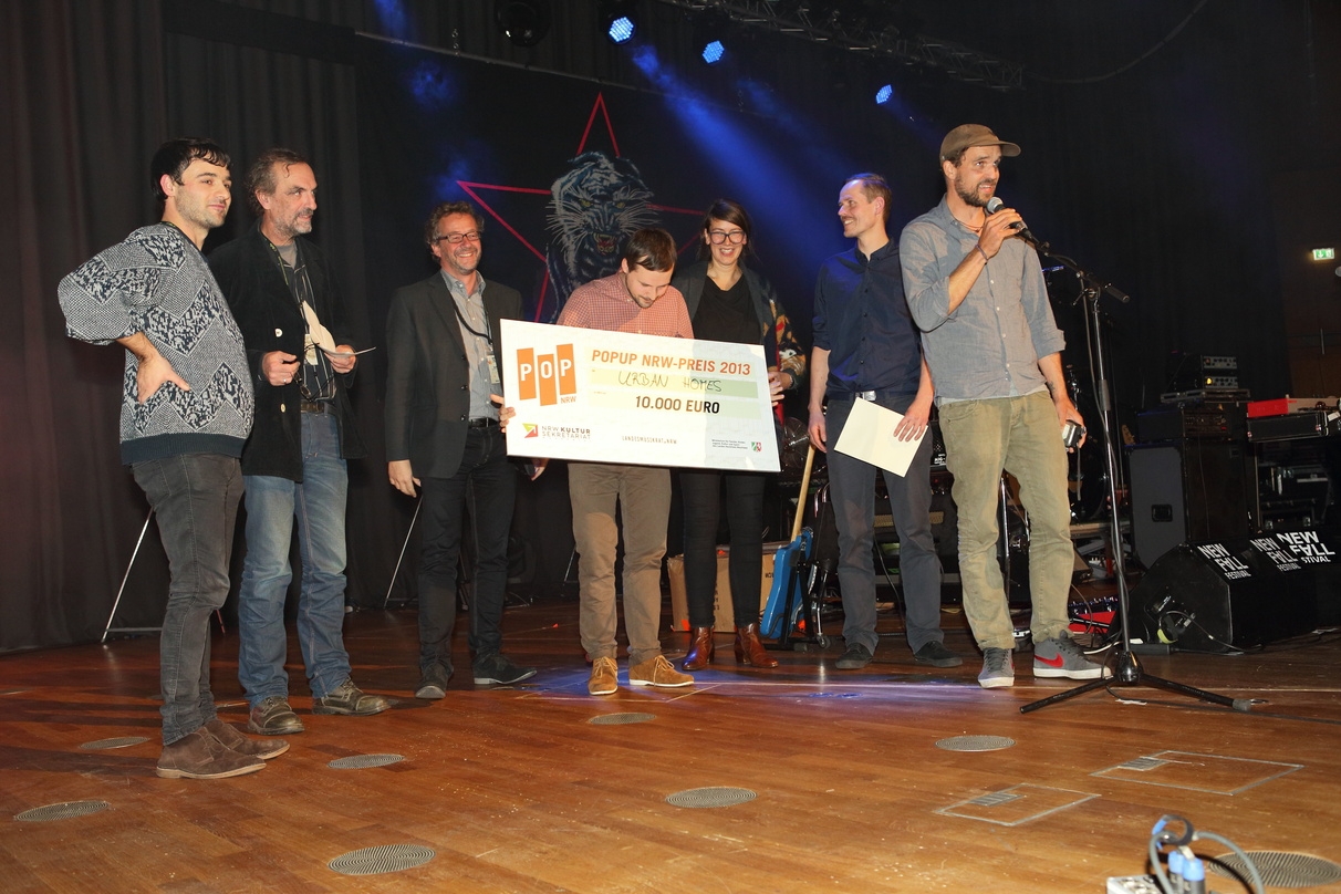 Ausgezeichnet: Die Siegerband 2013 Urban Homes mit Scheck und den popUP-NRW-Initiatoren auf der Bühne der Düsseldorfer Tonhalle.