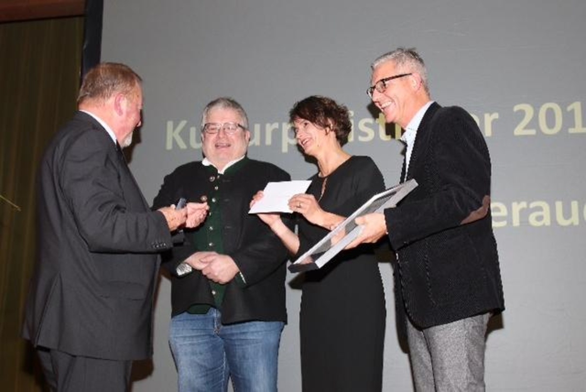 Der stellvertretende Landrat von Rosenheim, Josef Huber (links im Bild), überreichte den Kulturpreis des Landkreises Rosenheim an Benno Stigloher, Vanessa Lömker und Markus Aicher (v.l.n.r.) von den Musikfilmtagen Oberaudorf