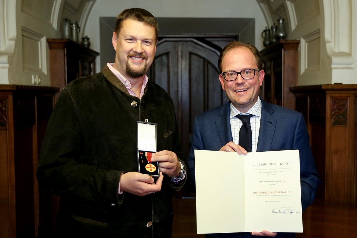 Münchens 2. Bürgermeister Manuel Pretzl (rechts im Bild) händigte Martin Blankemeyer den Verdienstorden der Bundesrepublik Deutschland aus