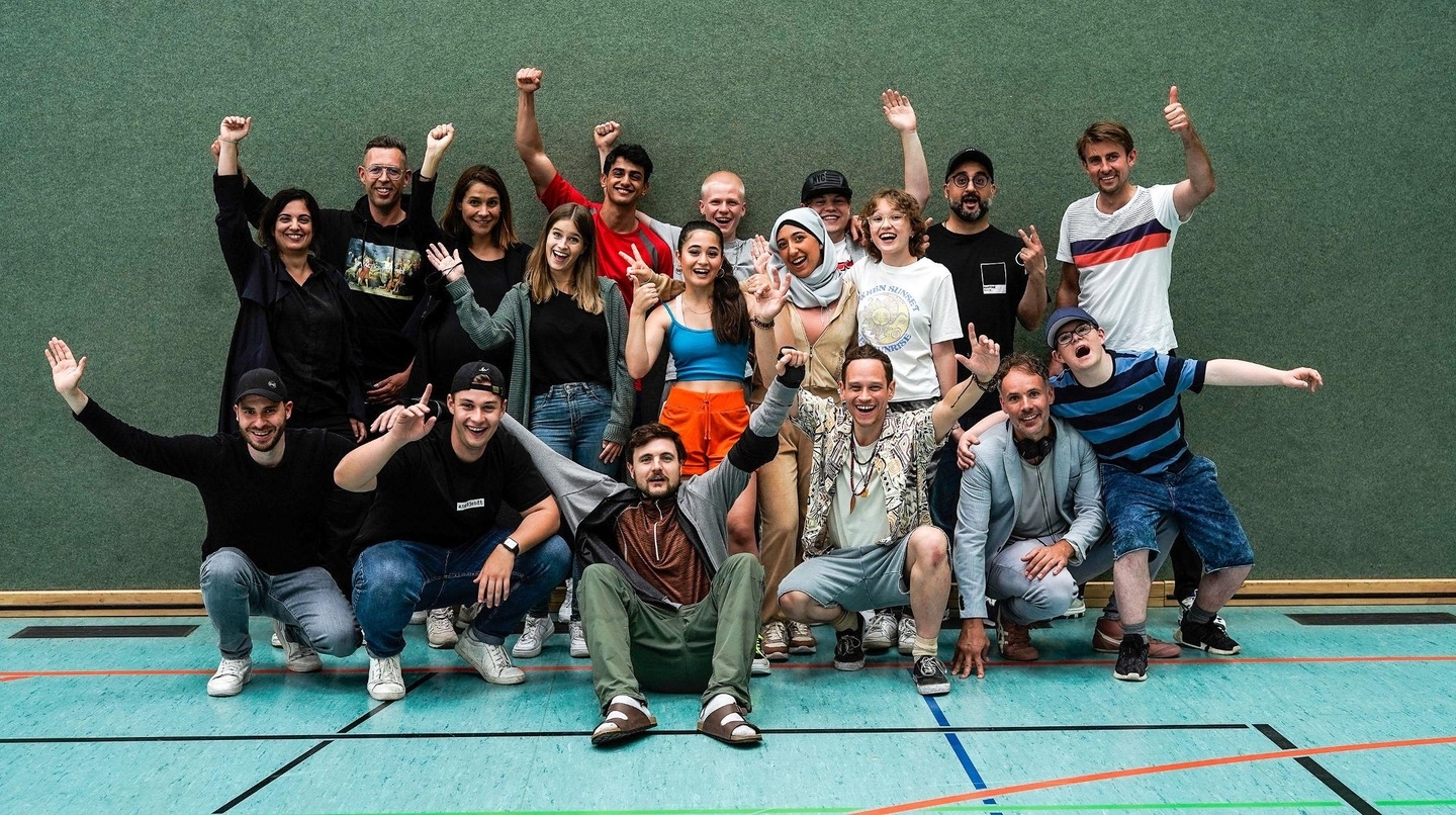 Am Set von "Almania": Marcus Nesseler (DiggiTales), Ben Poqué (DiggiTales), Phil Laude (Produzent DiggiTales, Hauptdarsteller & Showrunner), Vinzenz Kiefer (Darsteller), David Gruschka (Regie), Tim Alberti (Darsteller, vo., v.l.n.r.) und Rosh Khodabakhsh (Producerin DCM), Ralph Schiller (Produzent DiggiTales), Kirstin Wille (Produzentin DCM), Miriam Dane (DiggiTales), Mido Kotaini (Darsteller), Derya Dilber (Darstellerin), Leonid Roth (Darsteller), Jansel Dogan (Darstellerin), Vincent Hahnen (Darsteller), Matilda Smit (Darstellerin), Pesh Ramin (Drehbuchautor, Editor & Filmmusik), Johannes Thieme (Kamera, hi., v.l.n.r.)