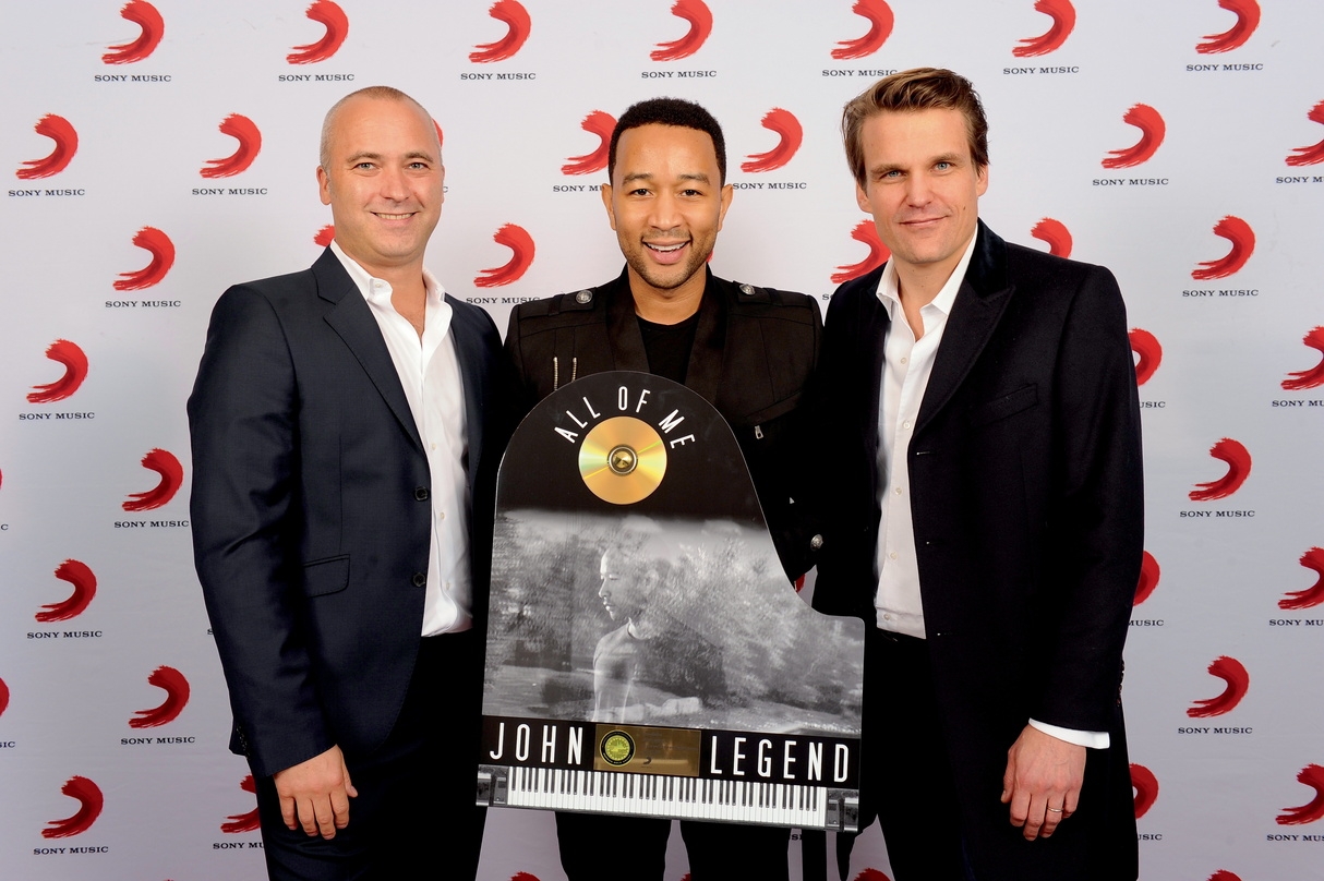 Trafen sich 2014 bei Laut in München (von links): Stefan Goebel (Senior Vice President International Sony Music), John Legend mit Edelmetall-Award und Philip Ginthör (CEO Sony Music GSA)